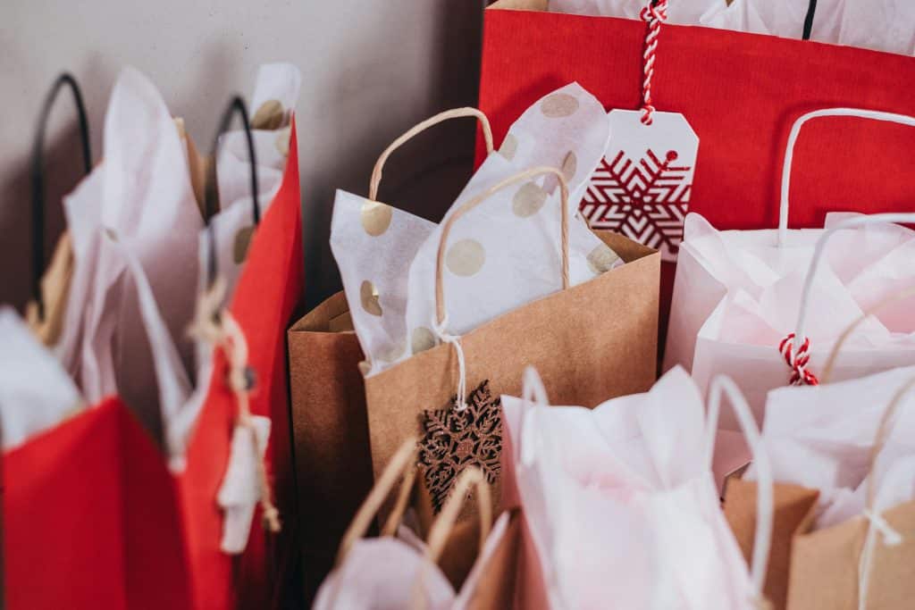 Collection of festive shopping bags filled with holiday gifts.